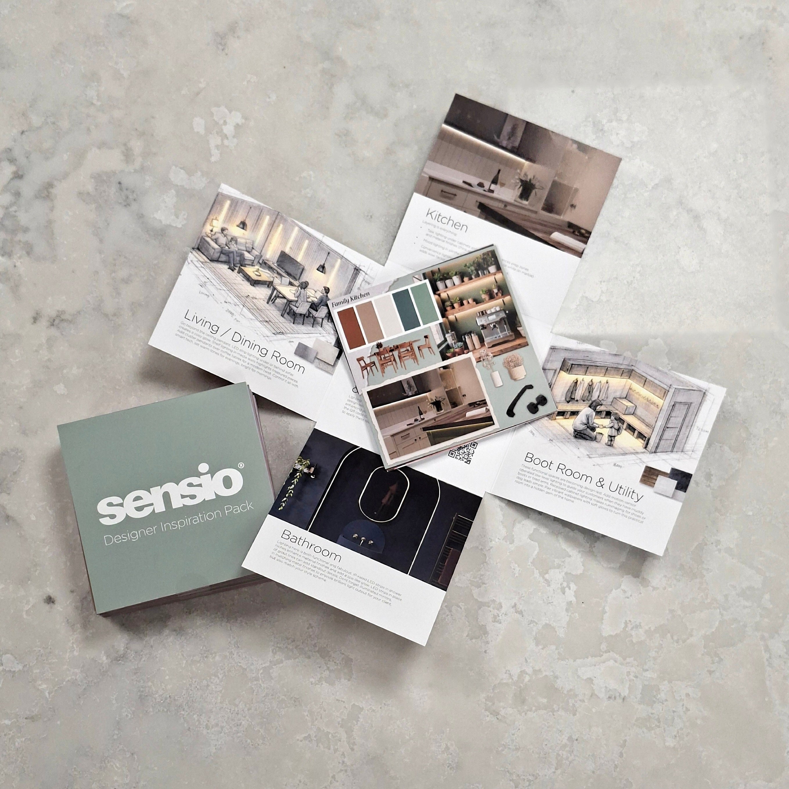 A Sensio designer inspiration pack set arranged on a textured light gray surface, featuring a muted sage green box labeled 'sensio designer inspiration pack' and several printed cards showing interior design inspiration images such as living/dining, kitchen, bedroom, and boat room & utility.