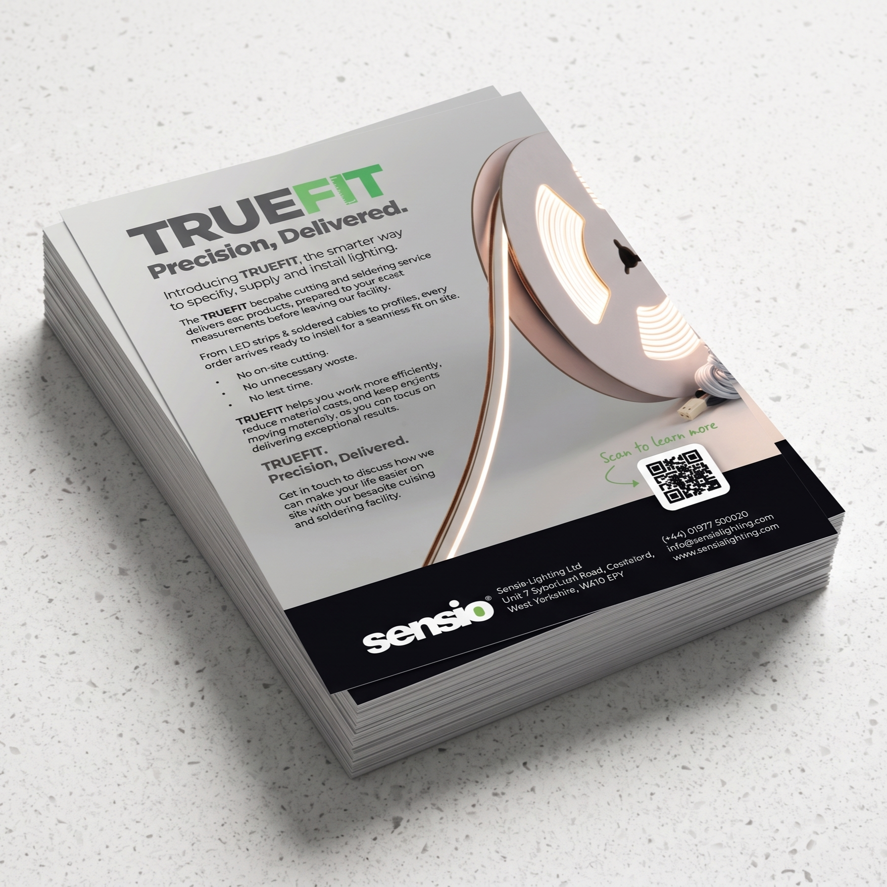 A stack of TrueFit precision LED light marketing cards and brochures from Sensio, displayed at an angle on a light speckled countertop. The cards feature a clean white and black design with green accents, showcasing the TrueFit lamp and product specifications.