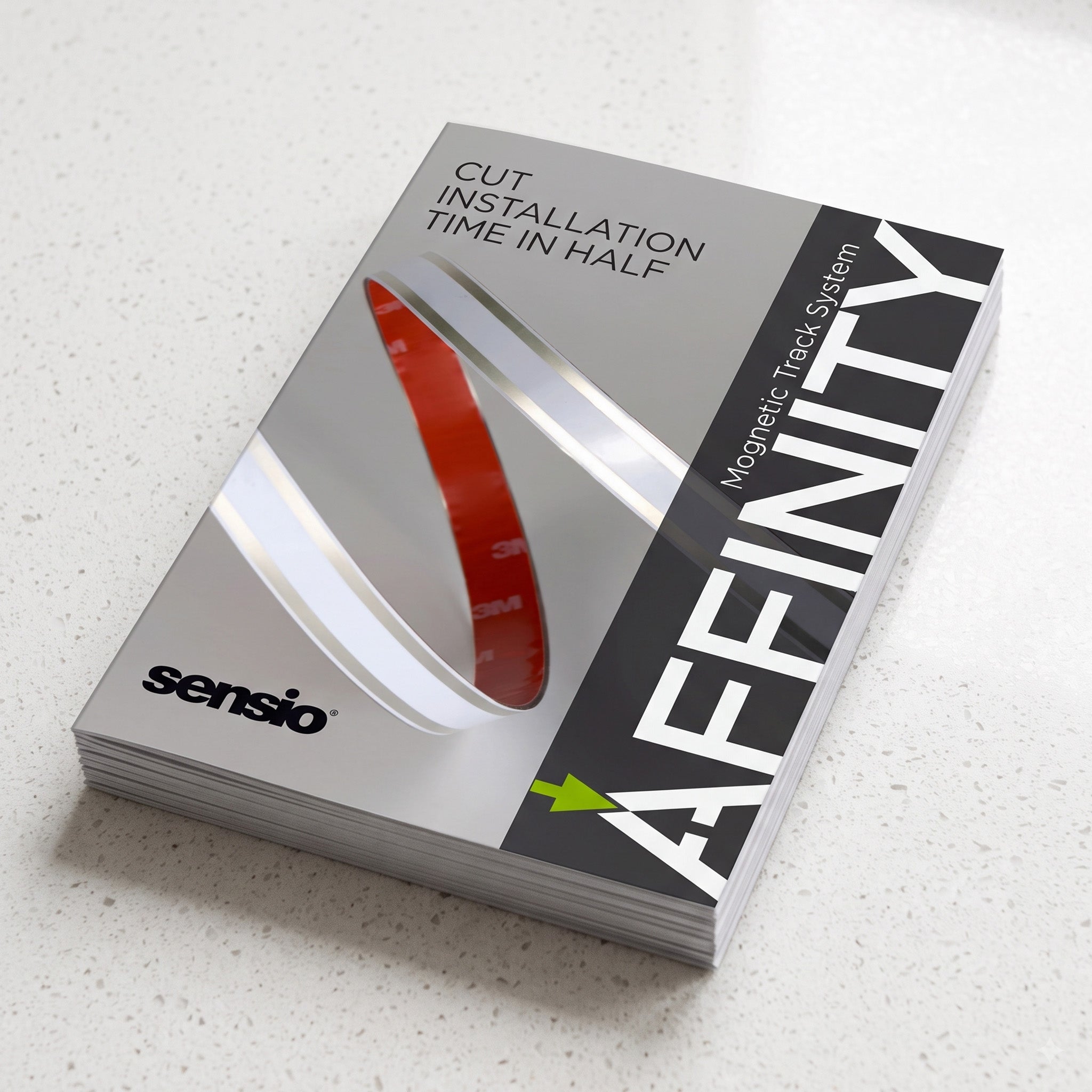 A stack of Sensio Affinity Magnetic Track System user manuals lying on a light speckled countertop. The manuals are silver and black with white text and a red graphic illustration.
