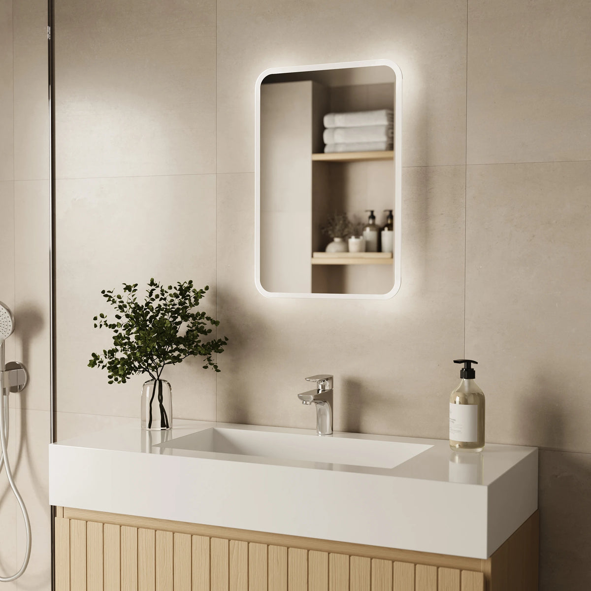 A modern bathroom vanity setup with a white rectangular sink, chrome faucet, a pump bottle on the counter, a vase with greenery, and a backlit rectangular wall mirror above. The background is a warm beige tiled wall. #Size_400mm x 600mm